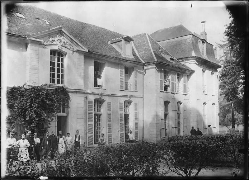 Groupe de malades et infirmiers devant l'hôpital et assis aux fenêtres